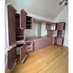 an empty kitchen with pink cabinets and wood flooring in the middle of the room