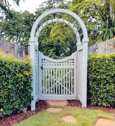 a white gate in the middle of a garden