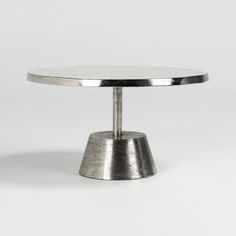 a round metal table with a white marble top on an isolated grey background, viewed from the front