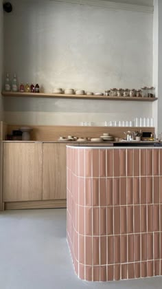 a counter with plates and cups on it in a room that has shelves above the counter