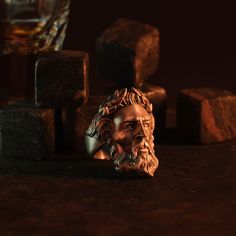 a bronze busturine is sitting next to some rocks and a glass on the table