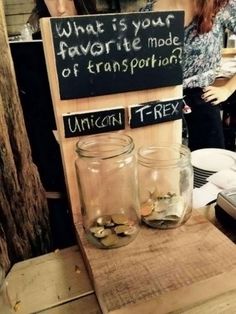 two jars filled with coins sitting on top of a wooden table next to a sign that says what is your favorite mode of transportation