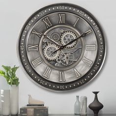 a large metal clock sitting on top of a table next to vases and books