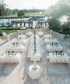 an outdoor dining area with tables and chairs set up for a formal function in front of the water