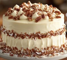 a cake with white frosting and pecans on top