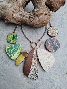 a necklace with different colored stones hanging from it's chain next to a piece of driftwood