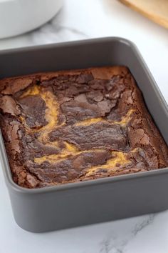 a square cake pan filled with brownies on top of a white marble countertop