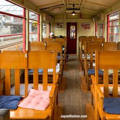 the inside of a train car with wooden benches and windows on both sides, along with blue blankets