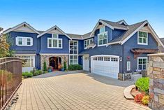 a large blue house with lots of windows on the front and side of it's driveway