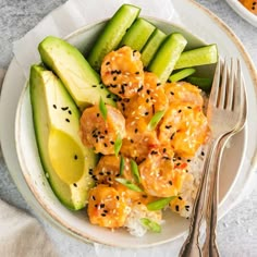 a white plate topped with shrimp and cucumber next to an avocado