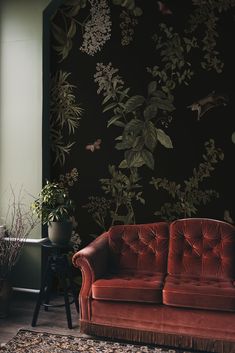 a red couch sitting in front of a black wall