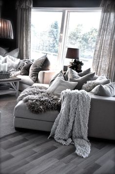 a living room filled with lots of furniture and pillows on top of a hard wood floor