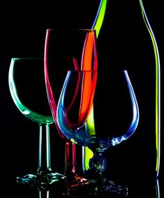 three wine glasses and a bottle on a reflective surface in black and white with reflection