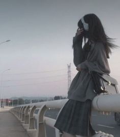 a woman standing on a bridge while talking on her cell phone