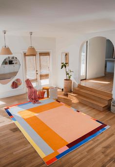 a living room filled with furniture and a rug on top of a hard wood floor