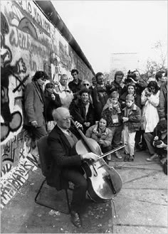 an old black and white photo of a man playing the cello in front of a group of people