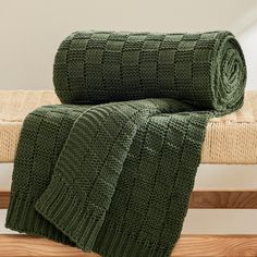 two green knitted blankets sitting on top of a wooden bench