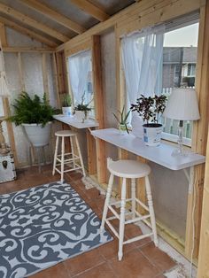 a room that has some stools and plants on it in front of the window