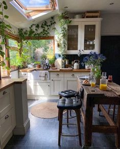 a kitchen filled with lots of counter top space and wooden stools under a skylight