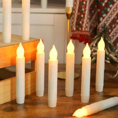 white candles are lined up on a wooden table