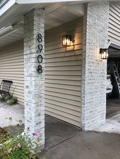 the front entrance to a building with two lights on each side and a car parked in the garage behind it