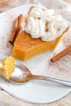 a slice of pumpkin pie with whipped cream on top and cinnamon sticks around the edges