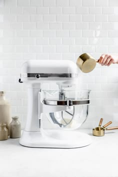 a person pouring something into a white mixer