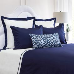 a bed with blue and white sheets and pillows