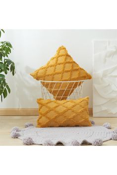 three pillows stacked on top of each other in front of a potted plant and rug