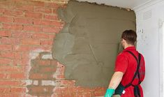 a man painting a brick wall with green paint