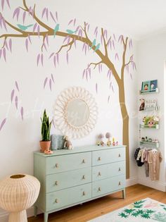 a tree painted on the wall in a child's room with pink and green leaves