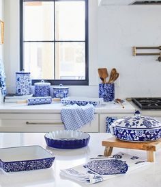 blue and white dishes sit on a counter in a kitchen with a window behind them