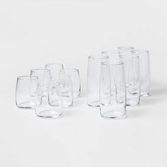 a bunch of glasses sitting next to each other on a white surface with one empty glass in the middle