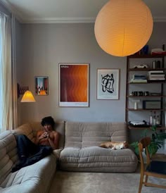 a man sitting on top of a couch in a living room next to a window