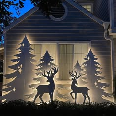 lighted christmas scene with deers and trees in front of a house