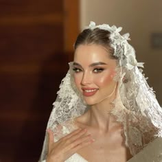 a woman in a wedding dress with a veil on her head and hands clasped to her chest