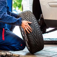 a man working on a tire in front of a car