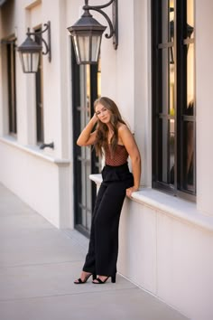 a woman leaning up against a wall with her hand on her head and looking at the camera