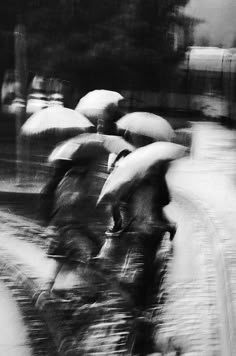 black and white photograph of people walking in the rain with umbrellas over their heads