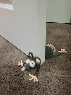 a crocheted mouse is laying on the floor next to a door frame and carpet