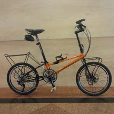 an orange and black bicycle parked in front of a wall with no one on it