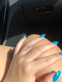 a woman with blue nails and a cross tattoo on her left hand