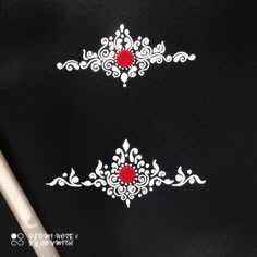 some white and red designs on a black cloth with a pen in front of it