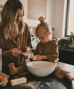 a woman and her daughter mixing together food in a bowl on the kitchen counter top