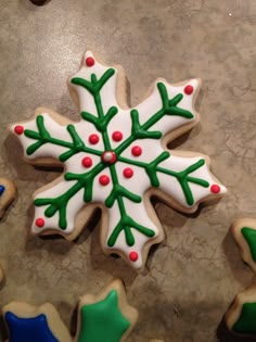 decorated cookies with green and white frosting on a counter top in the shape of a snowflake