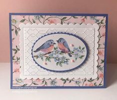 a card with two birds sitting on a flowery branch in front of a pink background