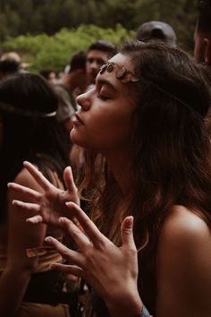 a woman standing in front of a crowd holding her hands out to the side and looking up