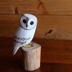 an owl figurine sitting on top of a piece of wood