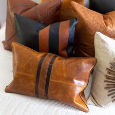 a bunch of pillows sitting on top of a white bed with brown and black stripes