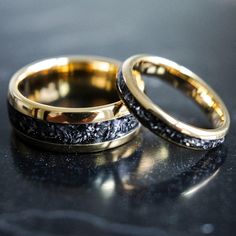 two gold wedding bands with black diamonds on them